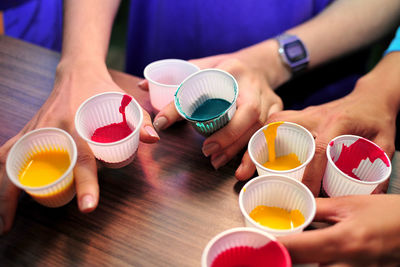 Close-up of people holding cups of paint