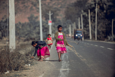 Rear view of women walking with pink umbrella on street