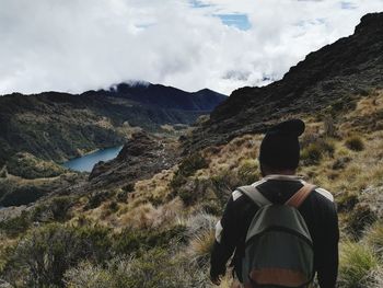 Rear view of man looking at mountains against sky