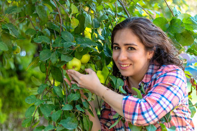 Portrait of smiling young woman against tree