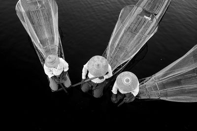 High angle view of men wearing asian style conical hat fishing while fishing in river