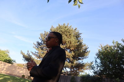 Low angle view of young man standing against sky