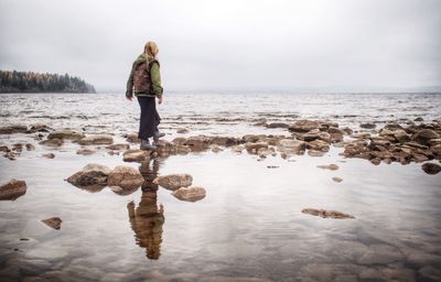 Rear view of woman standing on shore