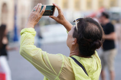 Side view of man photographing with mobile phone while standing outdoors