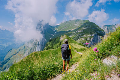 Rear view of man standing on mountain against sky