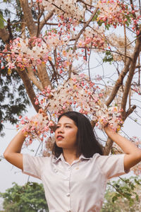 Portrait of young woman with cherry blossoms in spring