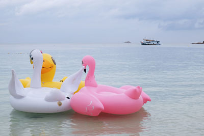 Bird shaped inflatable rafts in sea against sky