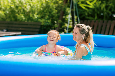 Cheerful healthy mother and daughter play in swimsuits in the pool. time together, summer time