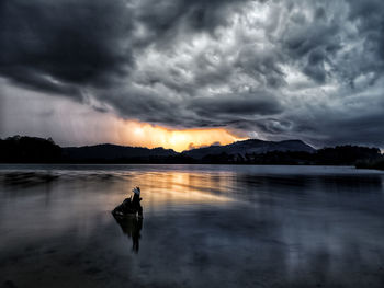 Scenic view of lake against dramatic sky