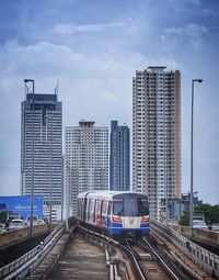 Railroad tracks amidst buildings in city against sky