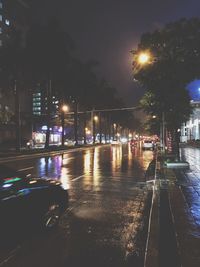 Illuminated city street against sky at night