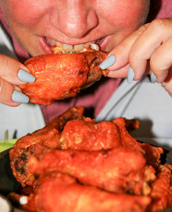 A close up of a person eating buffulo chicken wings. person