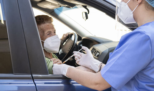 Senior woman getting covid-19 vaccine from female doctor at drive through