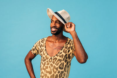 Young man wearing hat standing against blue sky