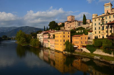 Buildings by lake against sky