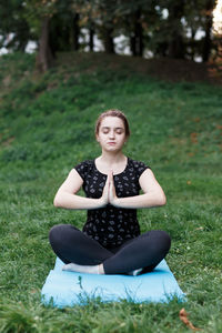 The relaxed girl is doing yoga in the park on carpet