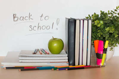 School supplies with apple and plant on table