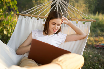 Midsection of woman using laptop while sitting on bed