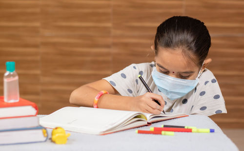 Girl looking away while sitting on table