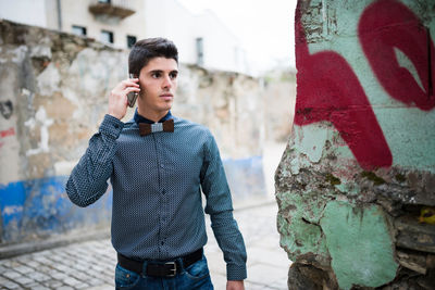 Young man looking away while talking on mobile phone