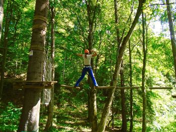 Woman walking on hanging logs in forest