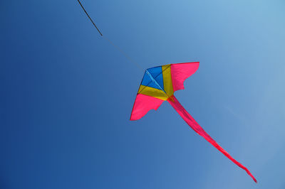 Low angle view of kite flying against clear blue sky