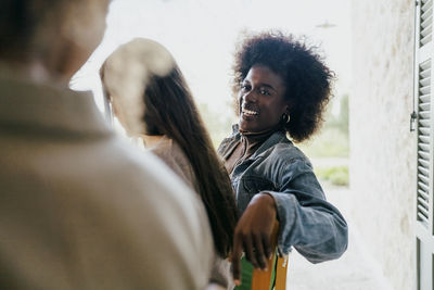 Happy woman with afro hairstyle sitting by female friends in patio