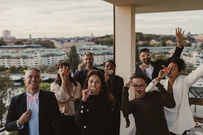 Portrait of cheerful business people with props having fun during company party