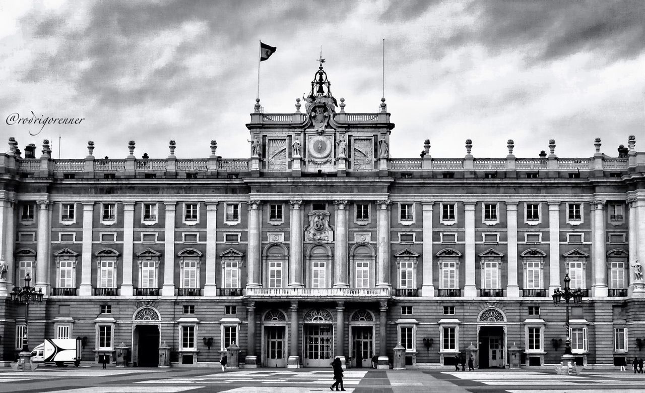 building exterior, architecture, built structure, sky, city, bird, flying, cloud - sky, facade, street, incidental people, cloudy, city life, low angle view, person, building, cloud, architectural column, travel destinations, town square