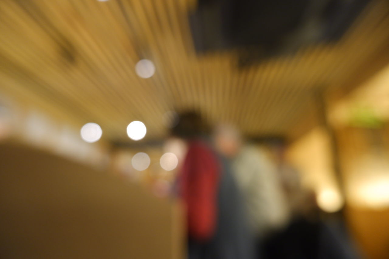 DEFOCUSED IMAGE OF PEOPLE WALKING IN ILLUMINATED UNDERGROUND LIGHTS