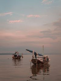 Fishing boat in sea against sky during sunset