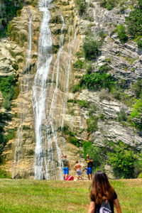 Rear view of people enjoying at waterfall