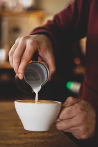 Midsection of barista preparing coffee in cafe