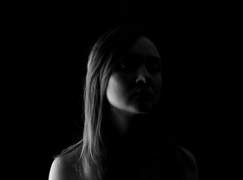 Close-up portrait of a young woman over black background