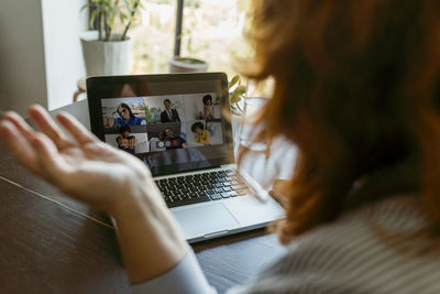 Woman using laptop while talking on video call at home