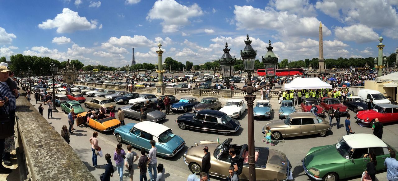 transportation, mode of transport, sky, building exterior, large group of people, built structure, moored, architecture, nautical vessel, cloud - sky, city, car, travel, harbor, panoramic, street, incidental people, in a row, land vehicle