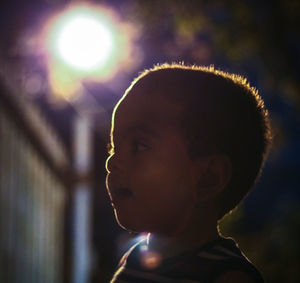 Close-up of boy against illuminated light