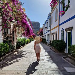 Rear view of woman walking on footpath in city