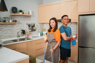 Portrait of young woman standing in kitchen