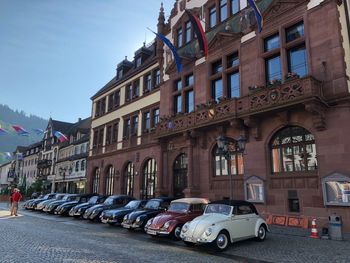 Cars parked on street by buildings against sky in city