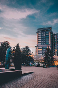 Statue in city against cloudy sky