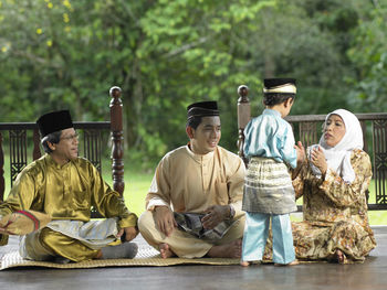 Family in traditional clothing sitting on mat