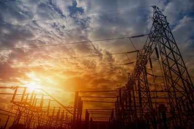 Low angle view of electricity pylon against sky during sunset