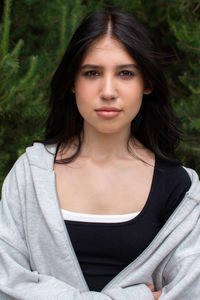 Portrait of young woman standing against trees