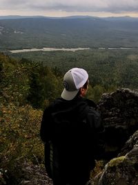 Rear view of man looking at mountains against sky