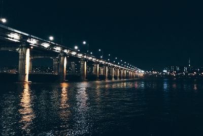 Illuminated bridge over river at night