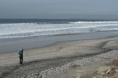 Rear view of person on beach against sky