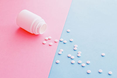 Directly above shot of pills spilling from bottle on table