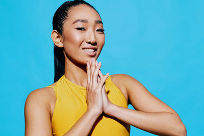 Portrait of young woman against blue background