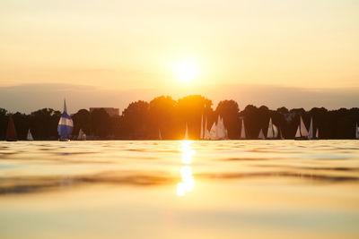 Rear view of people at beach against sky during sunset